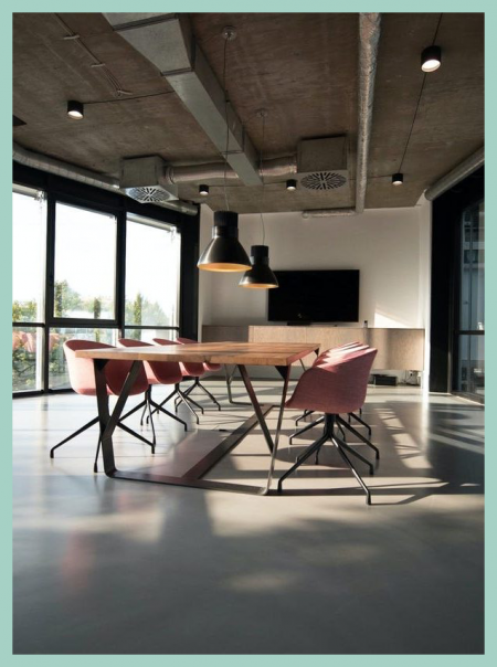 Man sieht ein sehr schönes Office, mit pinken Stühlen und einem großen Holztisch, dies zeigt das Büro von StudioX - Management & Consulting, Einer jungen Agentur aus Berlin